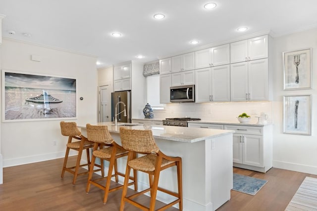 kitchen with a kitchen island with sink, white cabinetry, and stainless steel appliances