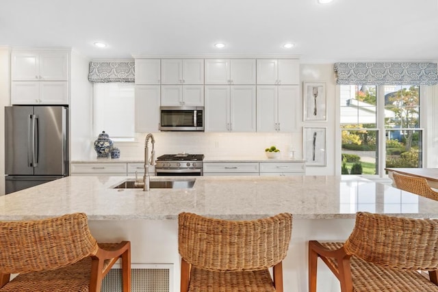 kitchen with a kitchen breakfast bar, white cabinets, stainless steel appliances, and sink