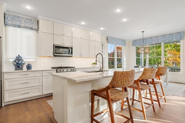 kitchen featuring stainless steel appliances, a wealth of natural light, hardwood / wood-style floors, and hanging light fixtures