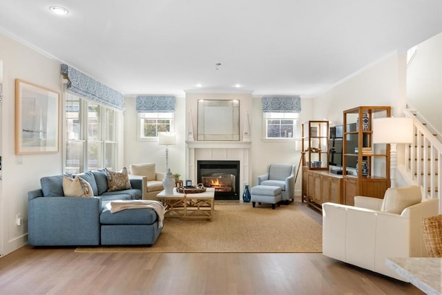 living room featuring ornamental molding, hardwood / wood-style floors, and a tile fireplace