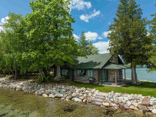 cabin featuring a water view and a front lawn