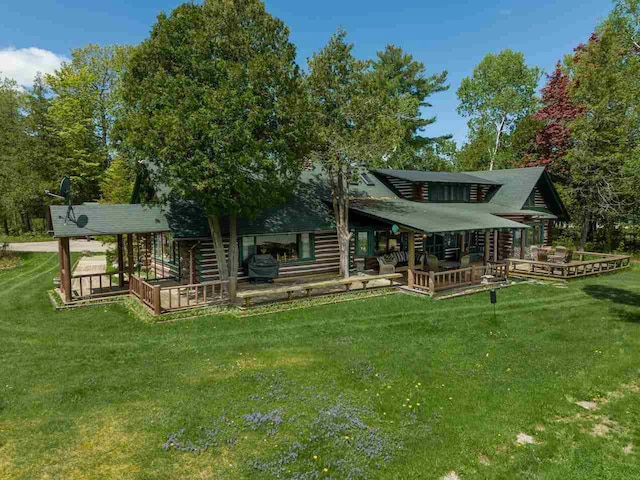 rear view of house featuring a wooden deck and a lawn