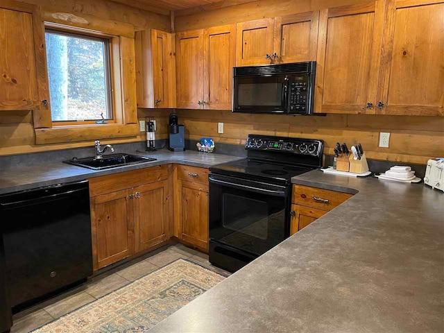 kitchen featuring light tile patterned floors, black appliances, sink, and wooden walls