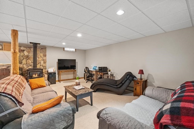 living room with a wood stove, a paneled ceiling, and carpet