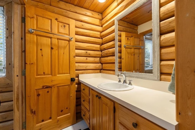 bathroom with log walls, wooden ceiling, and plenty of natural light