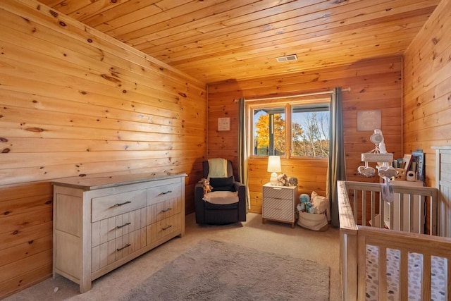 carpeted bedroom with wood ceiling, a crib, and wood walls