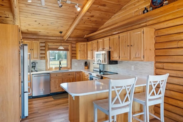 kitchen with appliances with stainless steel finishes, sink, kitchen peninsula, lofted ceiling, and pendant lighting