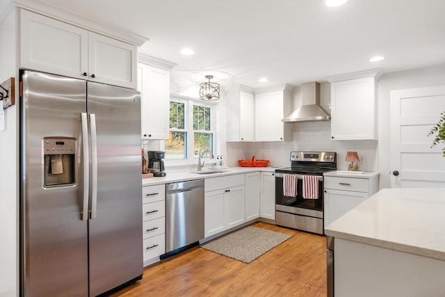 kitchen featuring wall chimney exhaust hood, stainless steel appliances, sink, white cabinets, and light hardwood / wood-style floors