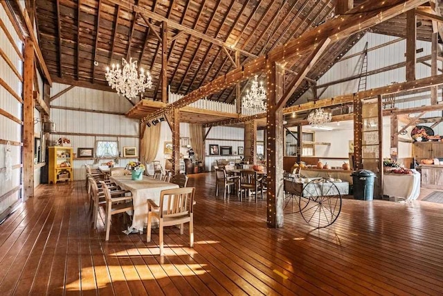 unfurnished dining area featuring a chandelier, wood-type flooring, and high vaulted ceiling