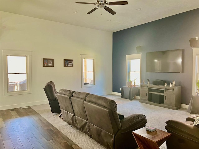 living room with hardwood / wood-style floors, high vaulted ceiling, ceiling fan, and a healthy amount of sunlight