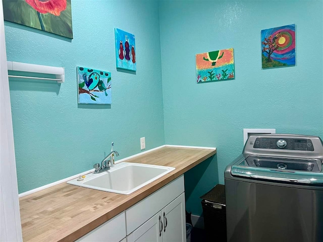 clothes washing area with washer / clothes dryer, sink, and cabinets