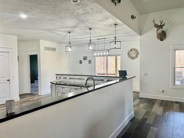 kitchen with tasteful backsplash, dark wood-type flooring, hanging light fixtures, and a healthy amount of sunlight