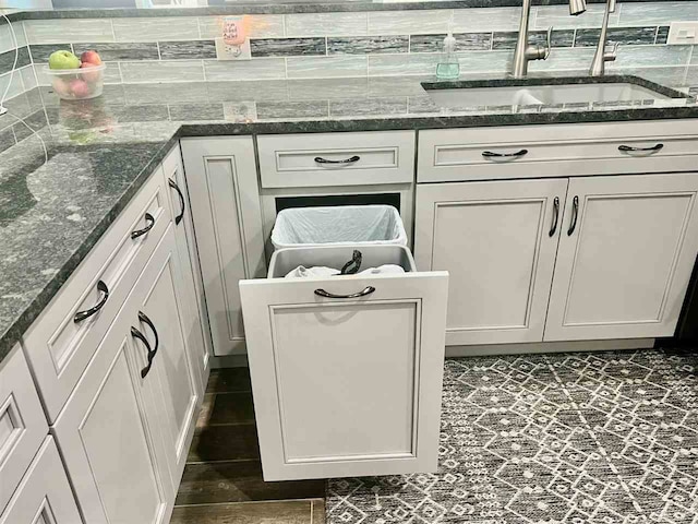 interior details featuring white cabinetry, dark stone counters, and sink