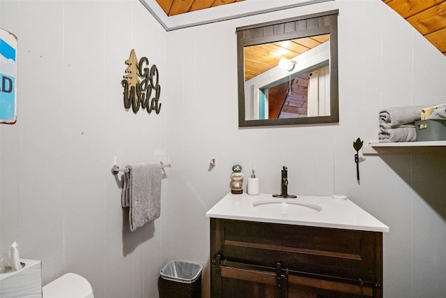 bathroom featuring vanity, wood ceiling, wood walls, and toilet