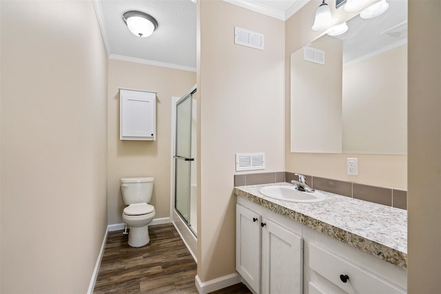 bathroom with a shower with door, toilet, wood-type flooring, ornamental molding, and vanity