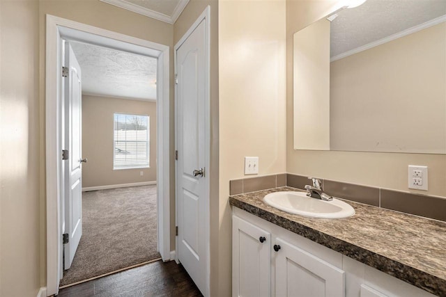 bathroom featuring crown molding, a textured ceiling, baseboards, and vanity