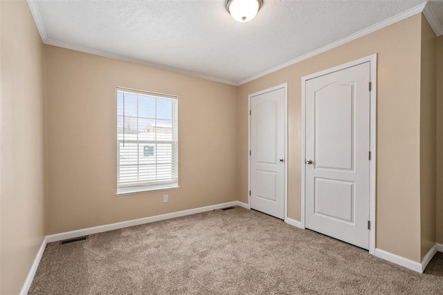 unfurnished bedroom with ornamental molding, carpet flooring, visible vents, and baseboards