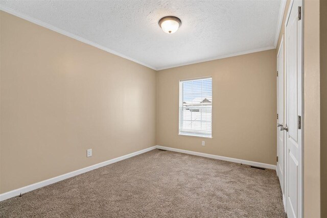 empty room featuring baseboards, carpet floors, crown molding, and a textured ceiling
