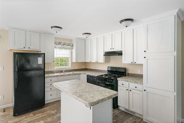 kitchen featuring hardwood / wood-style floors, white cabinetry, black appliances, sink, and a center island