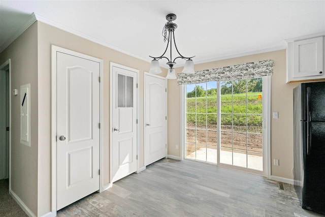 unfurnished dining area featuring ornamental molding, a notable chandelier, and light hardwood / wood-style floors