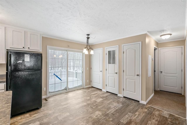 unfurnished dining area with a textured ceiling, wood finished floors, and baseboards