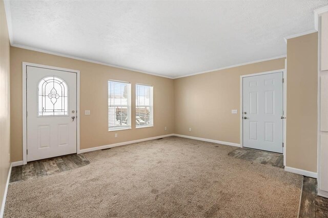 carpeted entrance foyer with baseboards, a healthy amount of sunlight, and crown molding