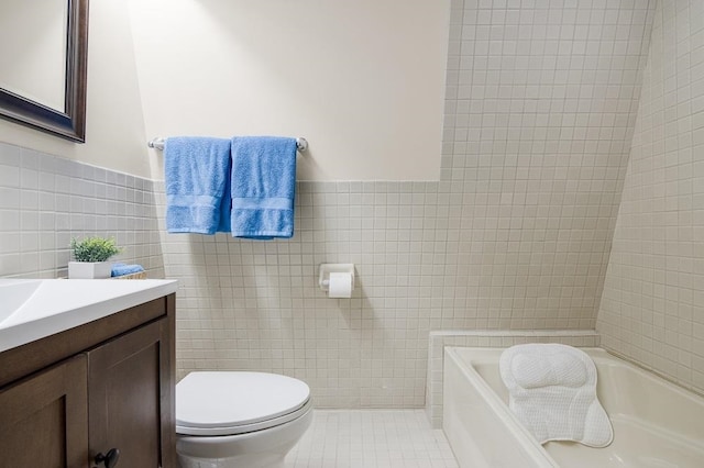 bathroom featuring vanity, a bathing tub, tile patterned floors, toilet, and tile walls