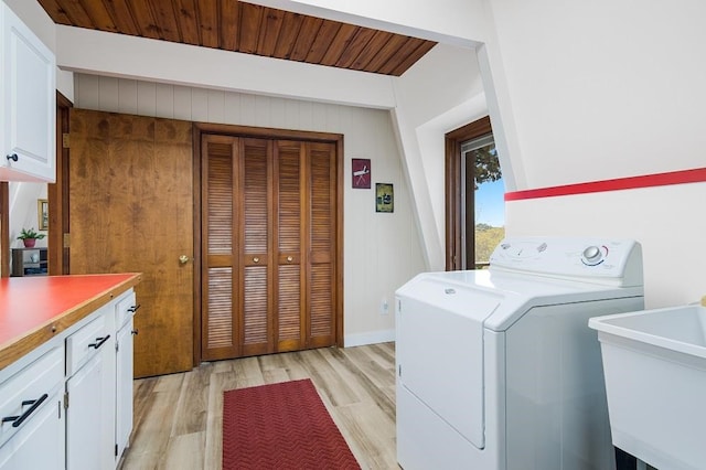 laundry area with cabinets, wooden walls, sink, light wood-type flooring, and washer / clothes dryer