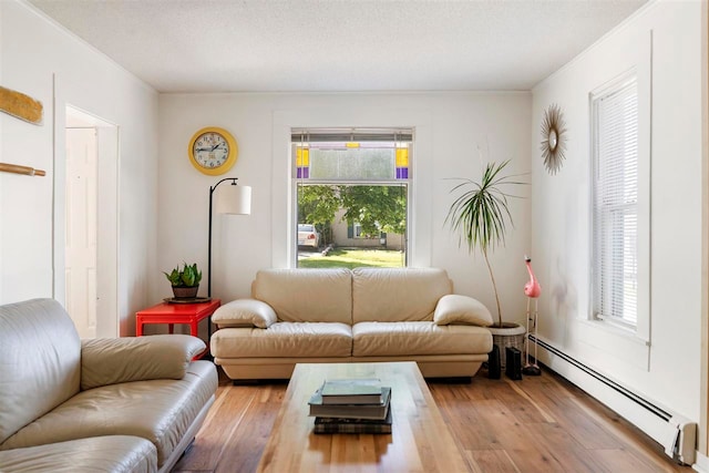 living room with hardwood / wood-style flooring, baseboard heating, and a textured ceiling