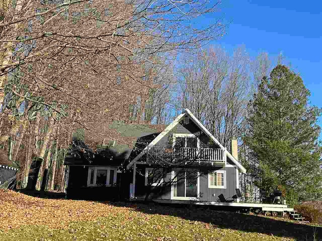 rear view of house featuring a wooden deck and a lawn