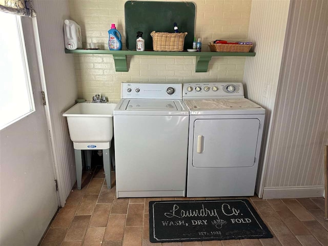 laundry area featuring light wood-type flooring, washer and clothes dryer, and sink