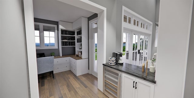 interior space with white cabinetry, beverage cooler, a healthy amount of sunlight, and light wood-type flooring