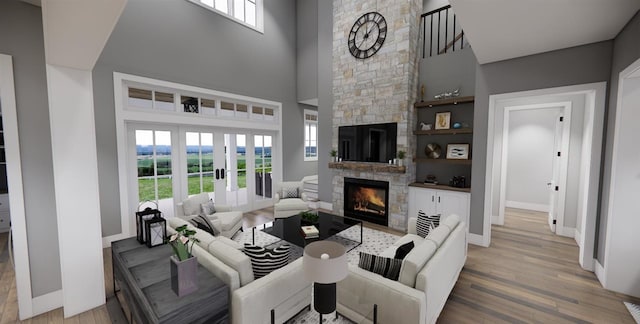 living room with a towering ceiling, a stone fireplace, and wood-type flooring