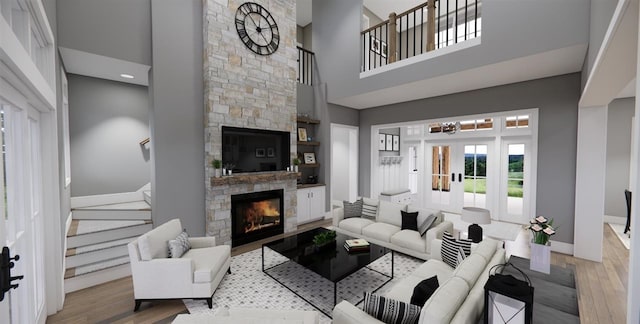 living room with a high ceiling, a stone fireplace, an inviting chandelier, and light wood-type flooring