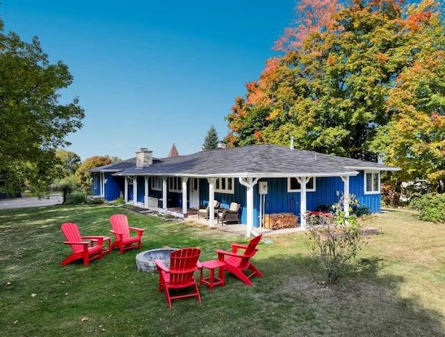 back of property featuring a fire pit, a lawn, and a patio