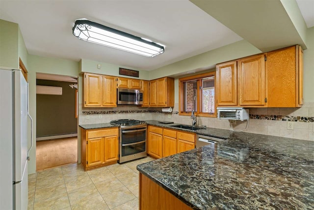 kitchen featuring decorative backsplash, appliances with stainless steel finishes, sink, and baseboard heating