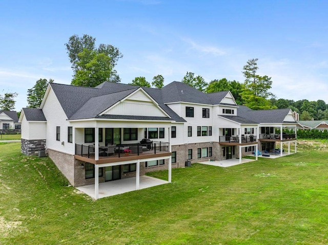 back of house featuring a patio, a lawn, and a wooden deck