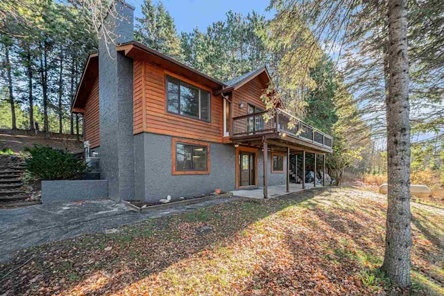 back of house featuring a wooden deck and a patio