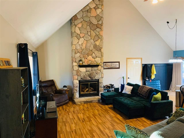 living room with a stone fireplace, a chandelier, high vaulted ceiling, and wood-type flooring