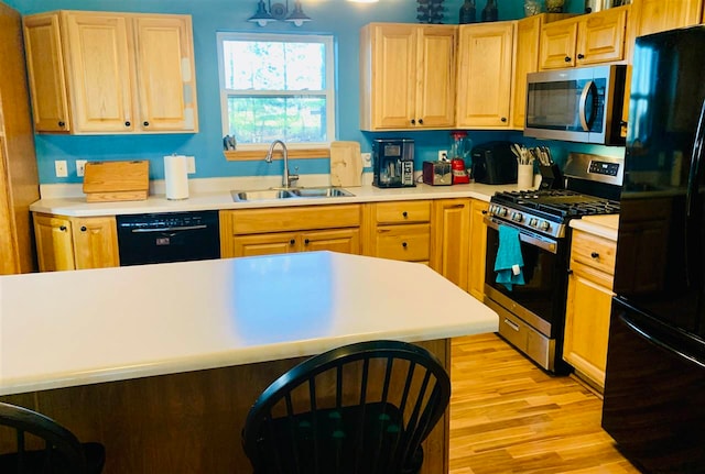 kitchen with black appliances, light wood-type flooring, and sink