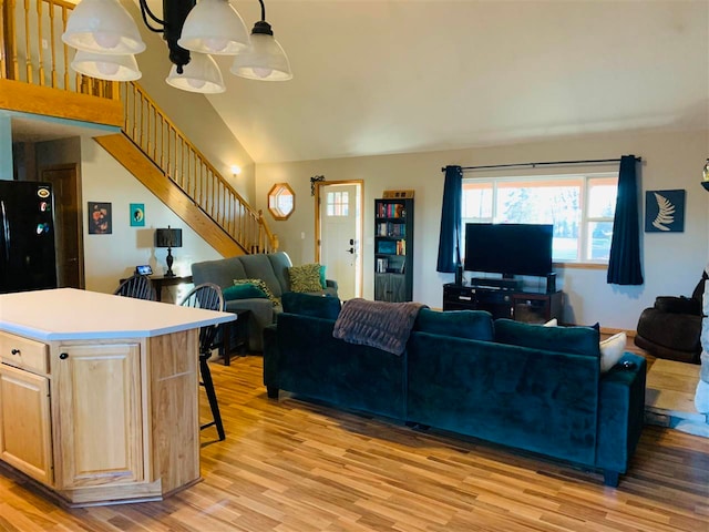 living room with light hardwood / wood-style flooring, a chandelier, and lofted ceiling