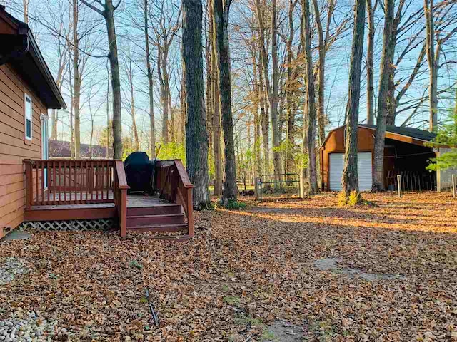 view of yard with a garage, an outdoor structure, and a wooden deck