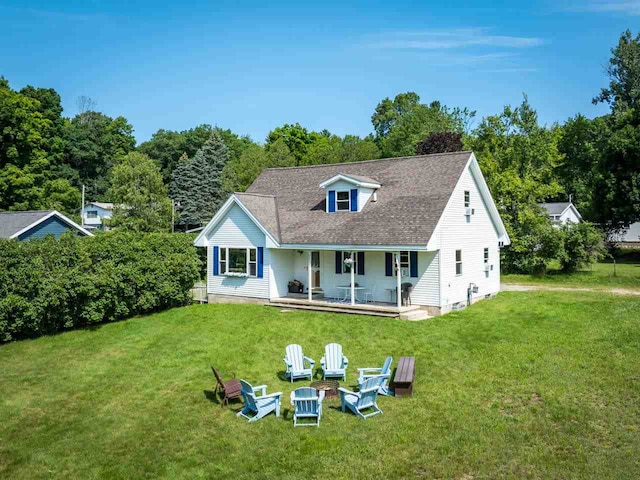 rear view of house with covered porch and a yard