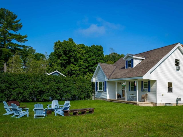 rear view of house with a lawn, a fire pit, and a porch