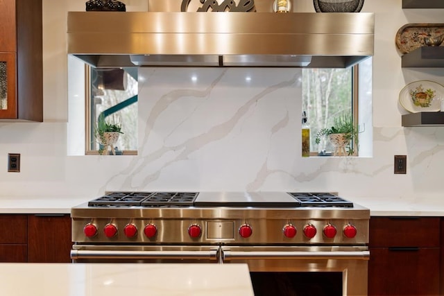 kitchen featuring backsplash, high end stainless steel range, and wall chimney range hood