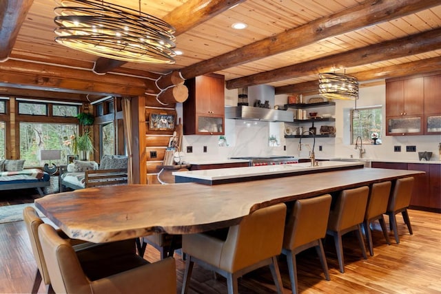 interior space with sink, wooden ceiling, beamed ceiling, range hood, and light wood-type flooring