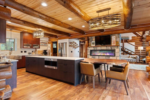 kitchen featuring sink, hanging light fixtures, a center island with sink, appliances with stainless steel finishes, and light wood-type flooring