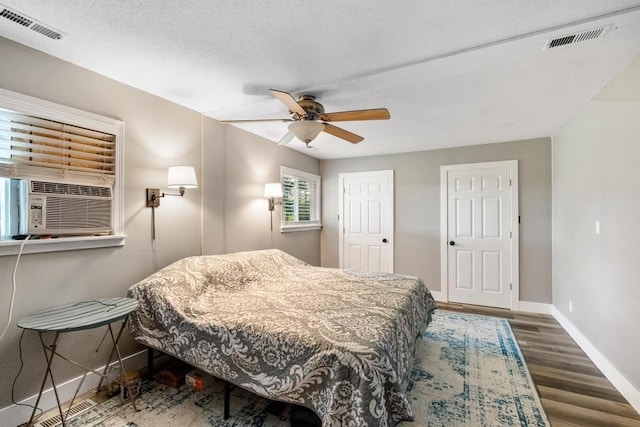 bedroom with ceiling fan, dark hardwood / wood-style flooring, and a textured ceiling