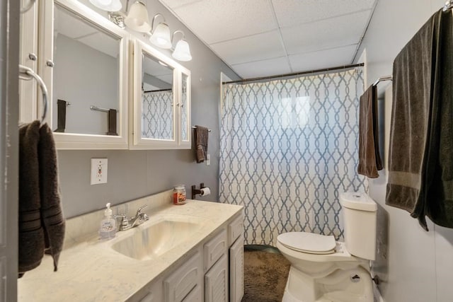 bathroom with a shower with curtain, a paneled ceiling, vanity, and toilet