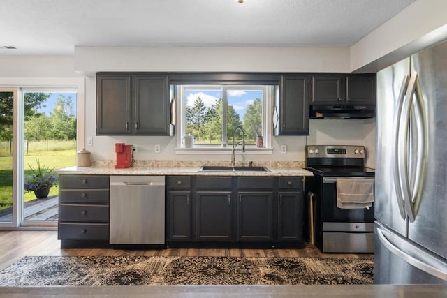 kitchen featuring light stone countertops, sink, dark hardwood / wood-style flooring, a textured ceiling, and appliances with stainless steel finishes